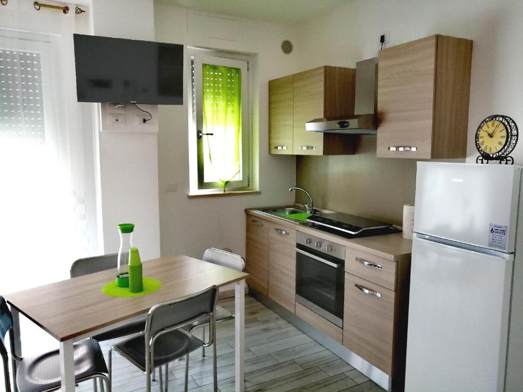 uma cozinha com uma mesa e um frigorífico branco em ALEXA casa vacanze em Pero