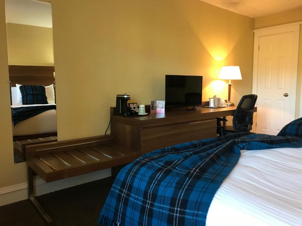 a hotel room with a bed and a desk at Inverary Resort in Baddeck