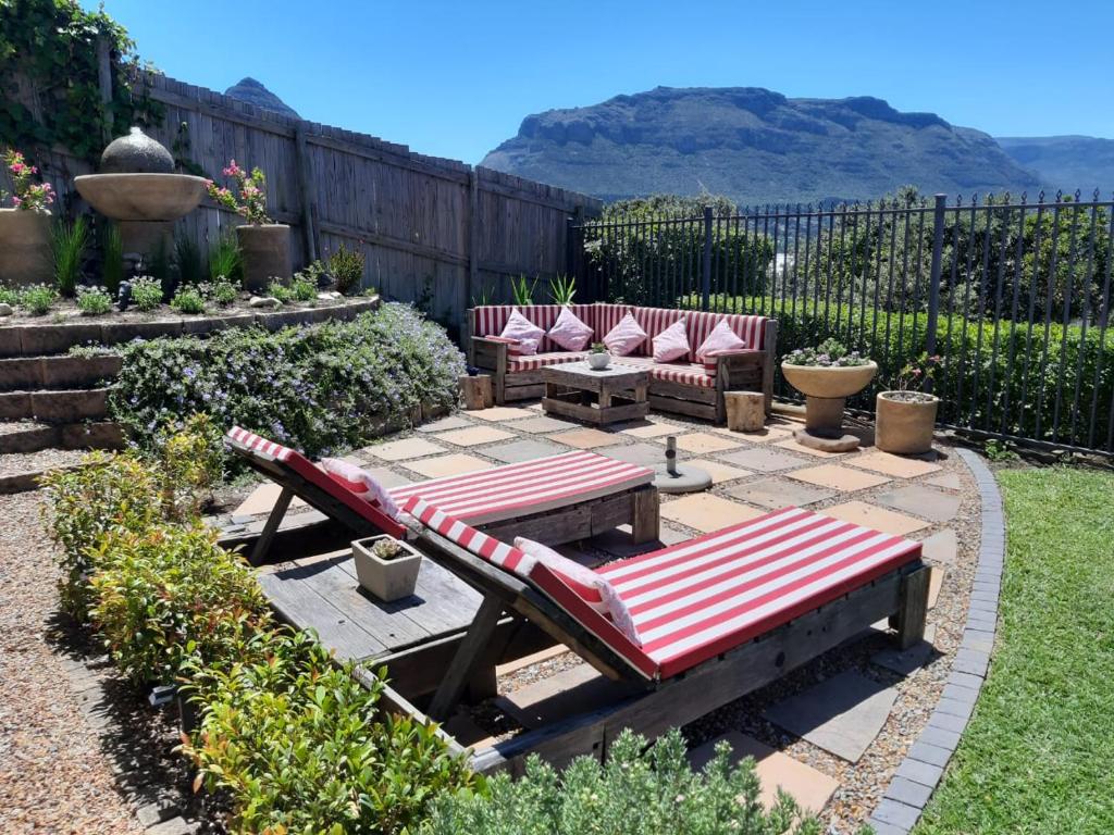 a patio with chairs and tables in a backyard at Sandpiper's Nest - Hout Bay in Hout Bay