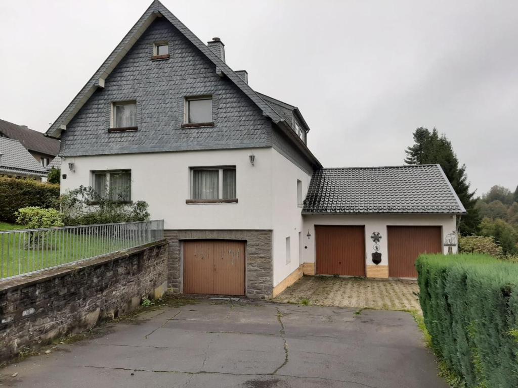 a white house with two garage doors and a driveway at Ferienwohnung auf Alzen in Alzen