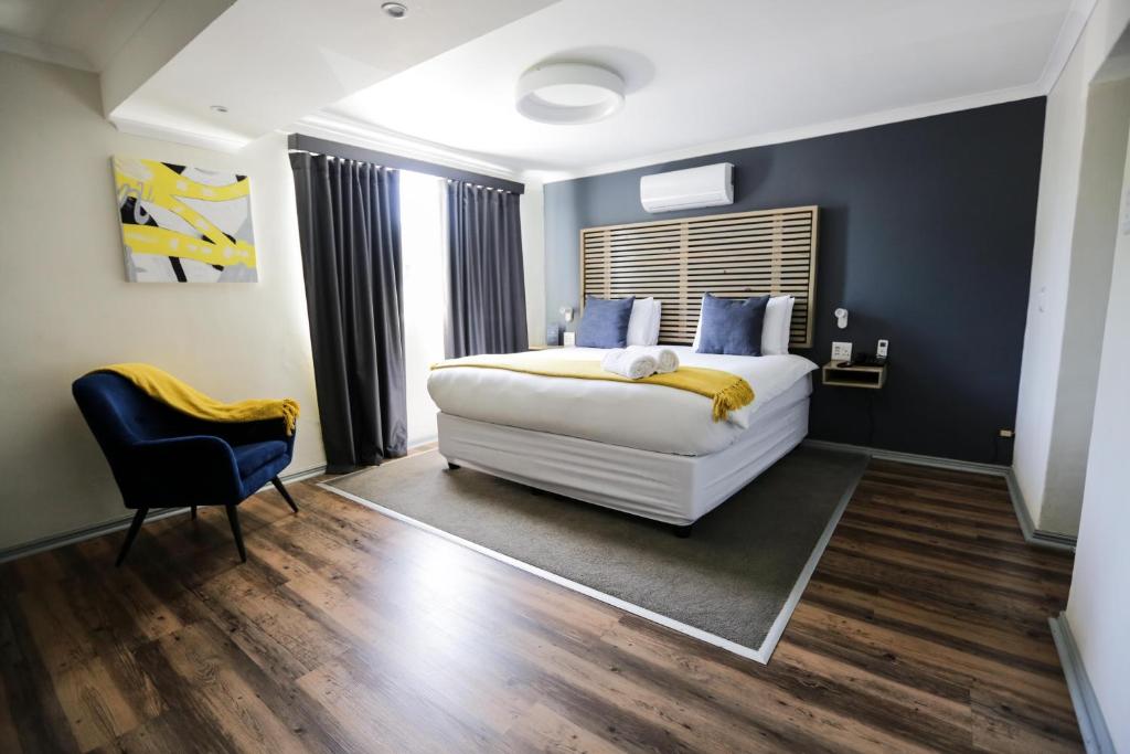 1 dormitorio con 1 cama blanca y 1 silla en New National Hotel and Conference en Parow
