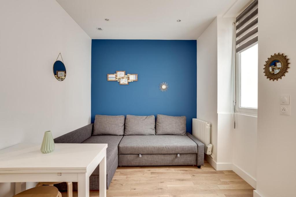 un salon avec un canapé et un mur bleu dans l'établissement Apartment 3 people close Eiffel Tower by Weekome, à Paris