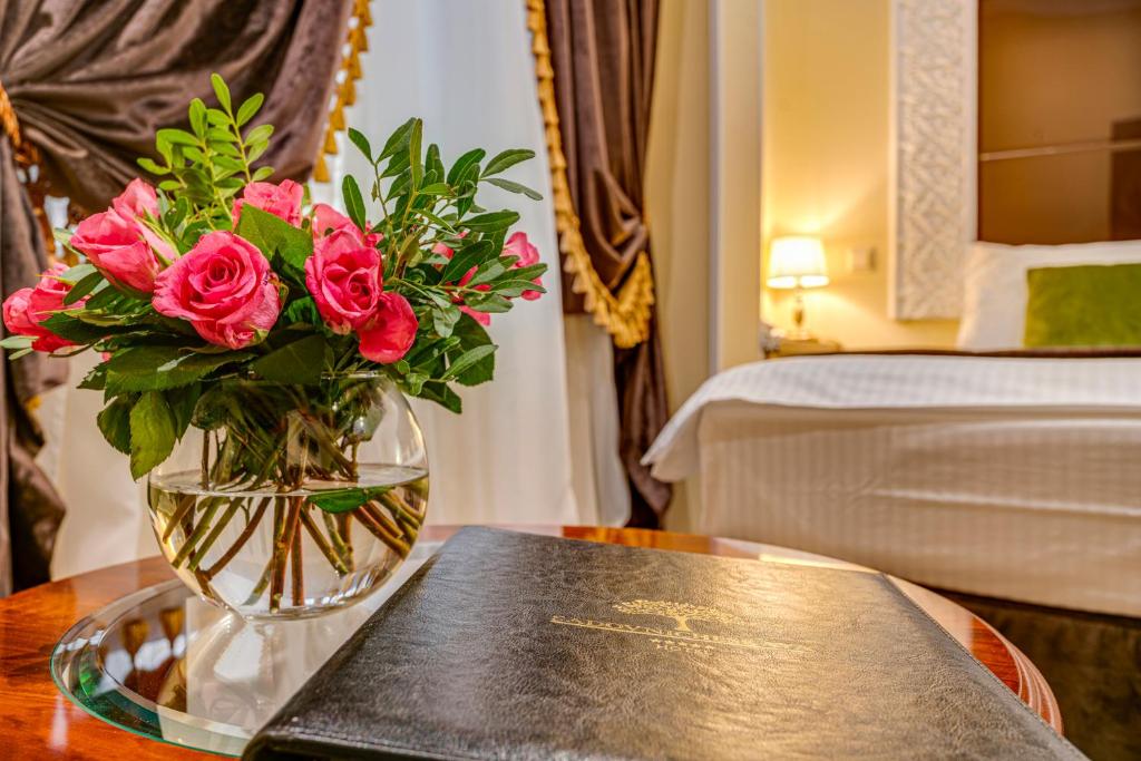 モスクワにあるホテル サドブニチェスカヤの本を読みながらテーブルに座るバラの花瓶