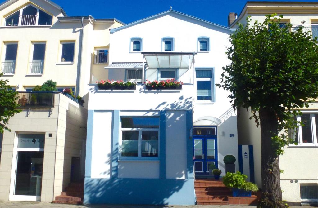 ein weißes Apartmenthaus mit blauer Tür in der Unterkunft Haus der kurzen Wege in Warnemünde