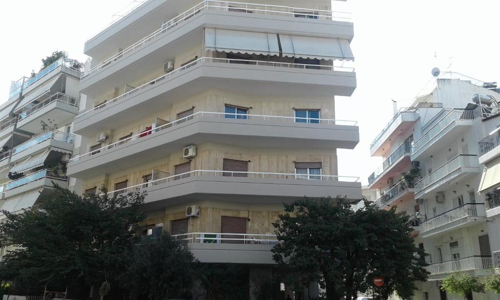 a tall white apartment building with balconies at Apartment 110 sqm free parking in Patra