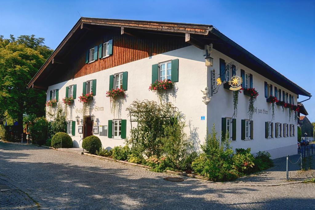 a white building with green shutters and flowers on it at Gasthof zum Stern in Seehausen am Staffelsee