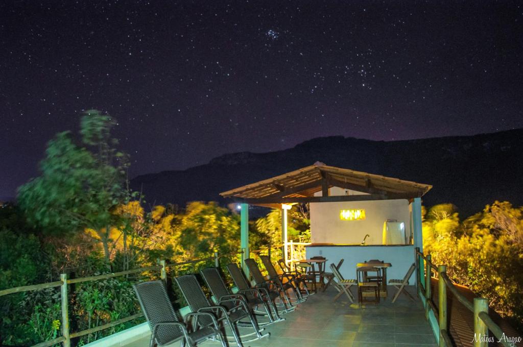 a group of chairs sitting on a deck at night at Entre Montanhas Capão in Vale do Capao