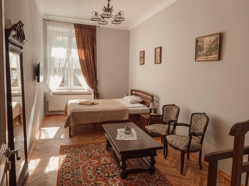 Schlafzimmer mit einem Bett, einem Tisch und Stühlen in der Unterkunft Kurnakh Apartment in Lwiw