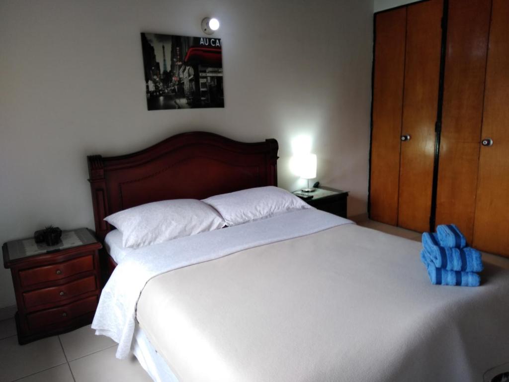 Un dormitorio con una cama grande con una mochila azul. en Hostal Norma101, en Bogotá