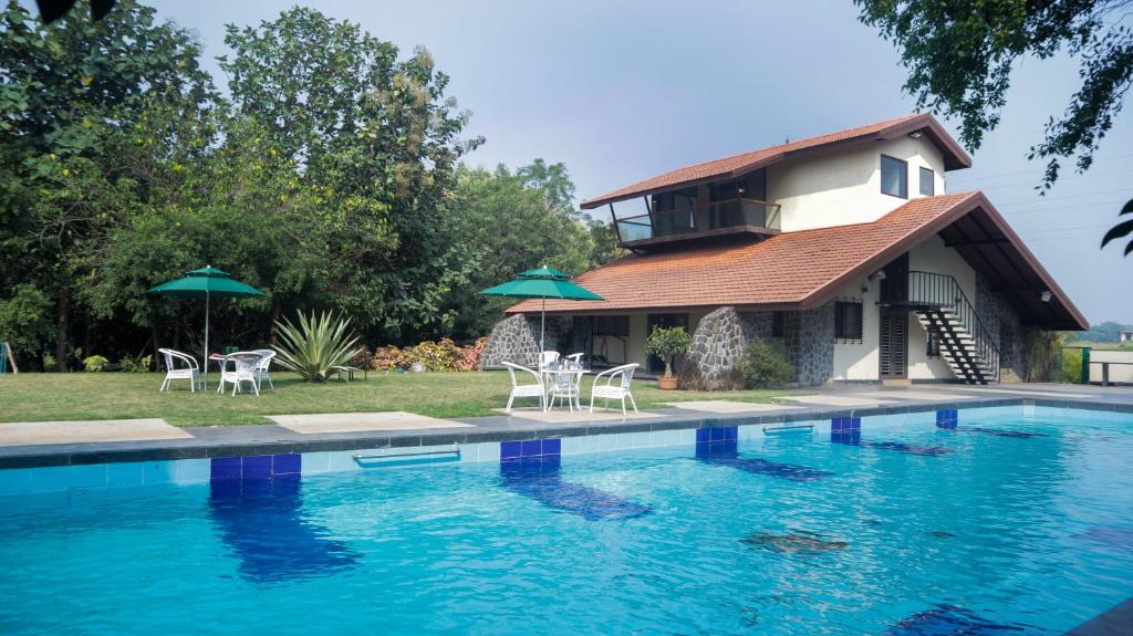 a house with a swimming pool with chairs and umbrellas at Jungle Safari Resort & Holiday Villa in Nashik