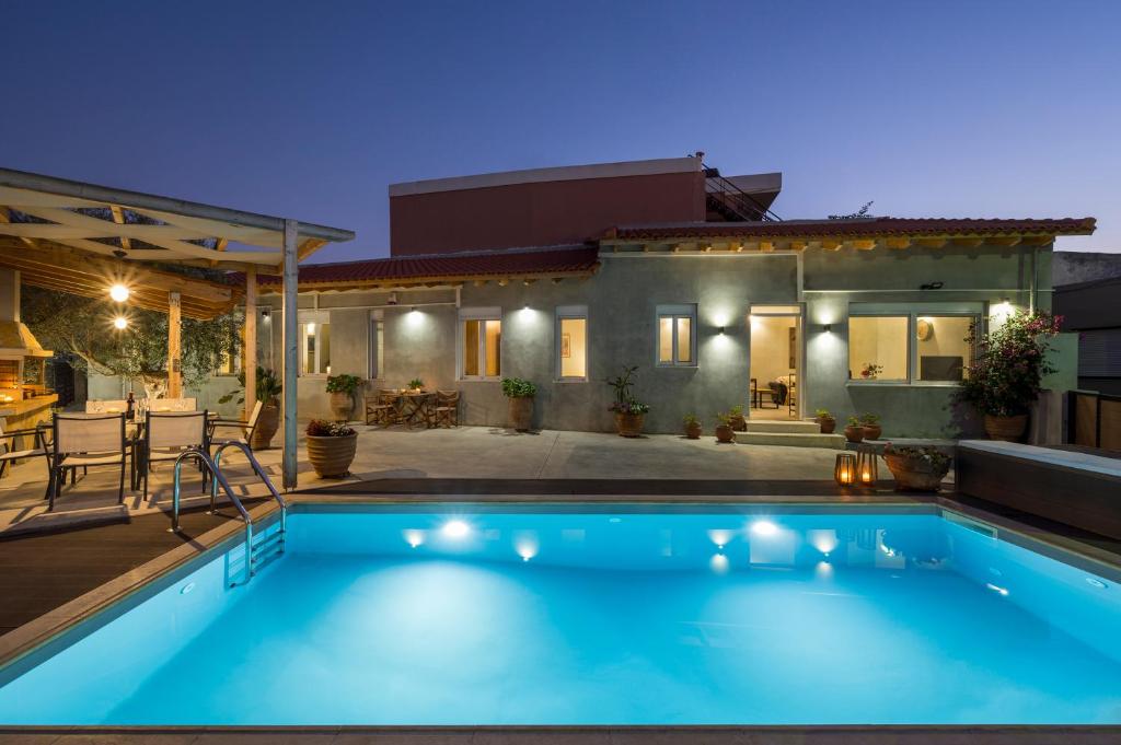 - une piscine en face d'une maison la nuit dans l'établissement Villa Roxanne, à Galatás