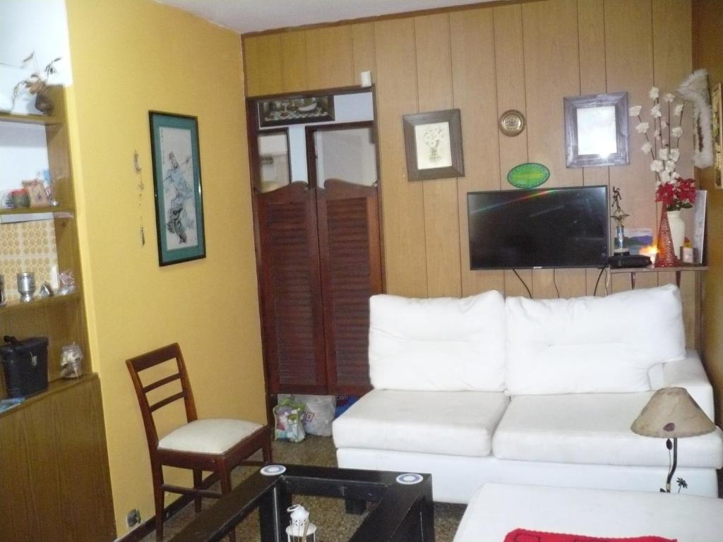 sala de estar con sofá blanco y TV en mar de ajo norte dto. 3 amb frente al mar P.B. en Mar de Ajó