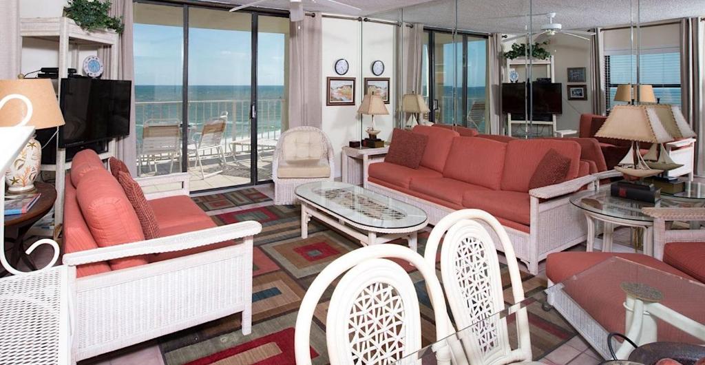 uma sala de estar com um sofá vermelho e cadeiras em Sunswept 701 Condo em Orange Beach