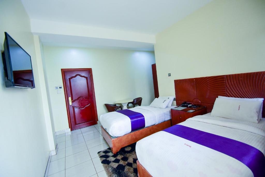 ein Hotelzimmer mit zwei Betten und einem Fernseher in der Unterkunft Hotel OK Kampala in Kampala