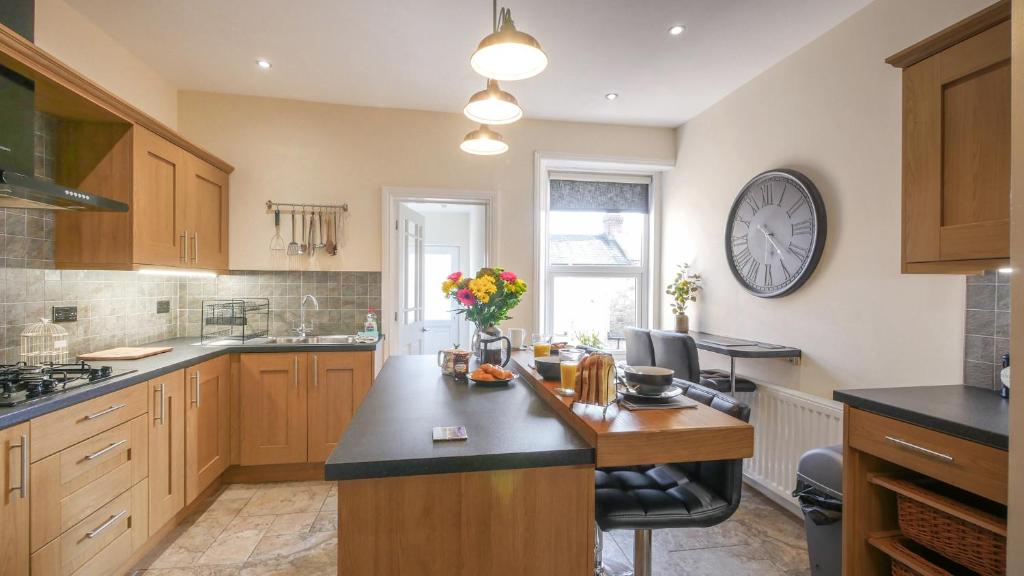 a kitchen with wooden cabinets and a clock on the wall at The Abbey Apartment in Hexham