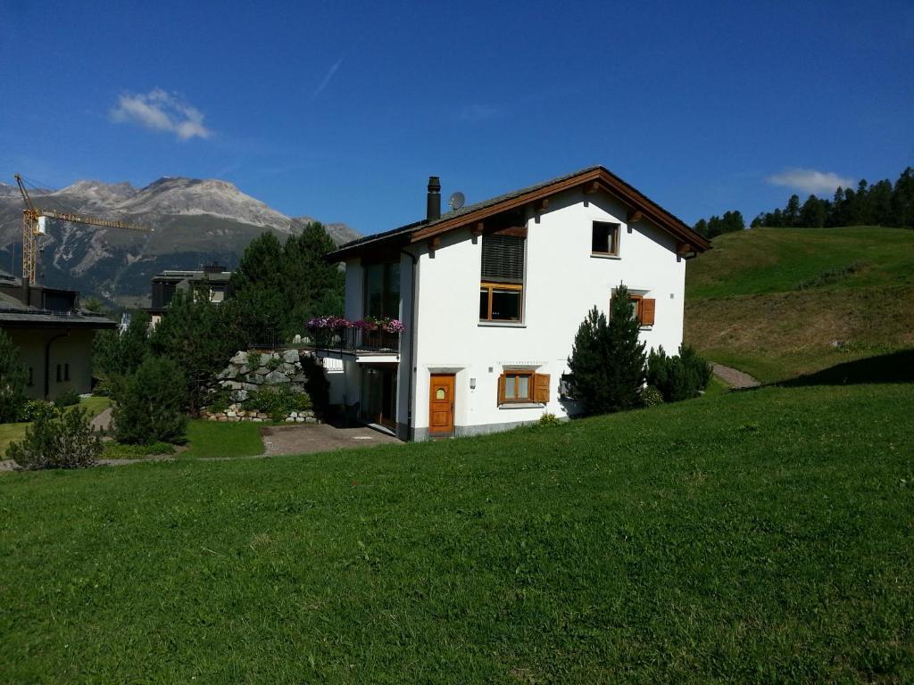 a white house on top of a green hill at Chesa Ovelin in Pontresina