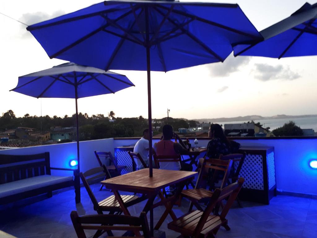 a group of people sitting at a table with umbrellas at La Estacion Hostel - Pipa in Pipa