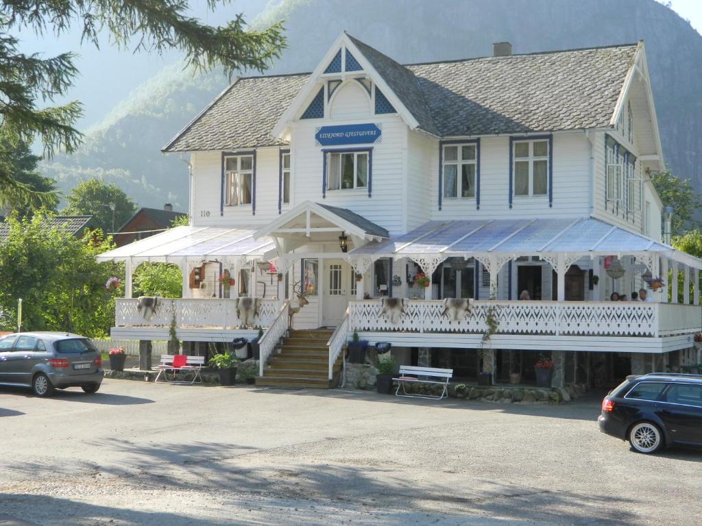 een groot wit huis met een winkel op een parkeerplaats bij Eidfjord Gjestgiveri in Eidfjord