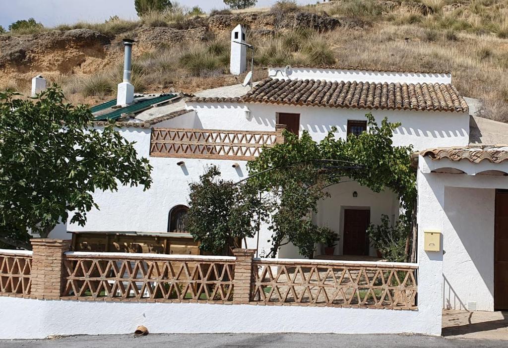una casa blanca con una valla de madera alrededor en Casa Cueva Pastor, en Fontanar