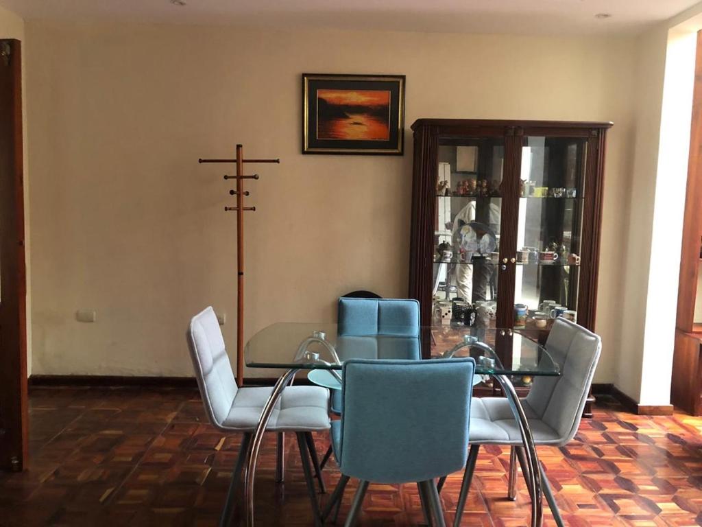 uma sala de jantar com uma mesa de vidro e cadeiras em Mini departamento cómodo em Cuenca
