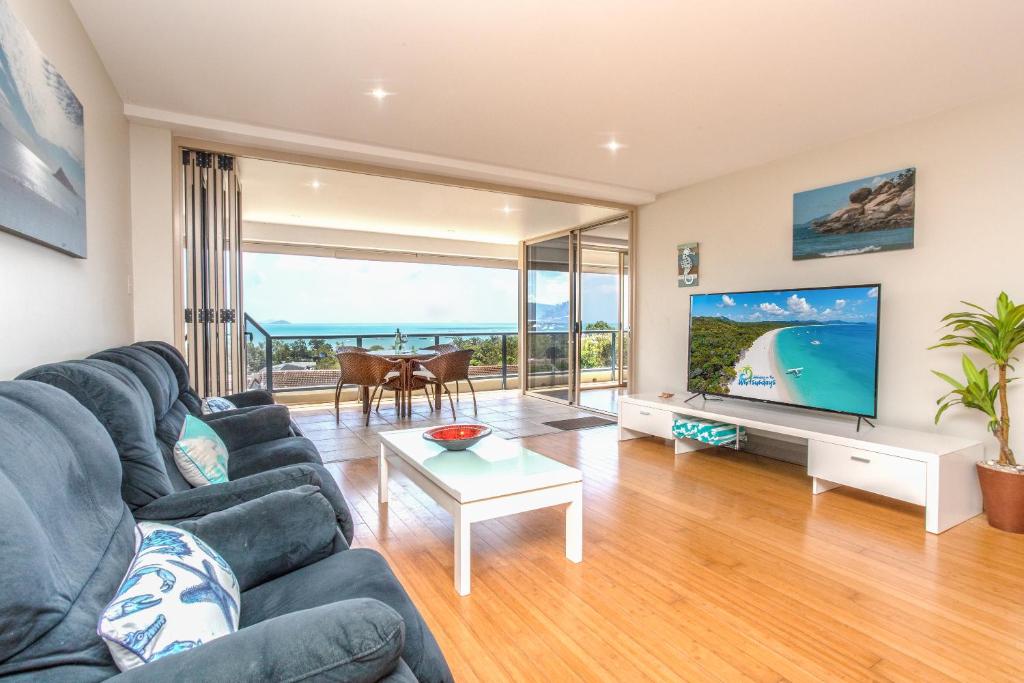 a living room with a couch and a large screen tv at VIEWS ON ELSHEBY in Airlie Beach