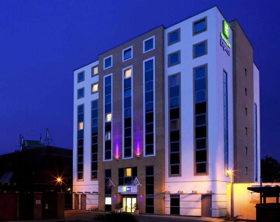 Holiday Inn Express London - Watford Junction, an IHG Hotel في واتفورد: مبنى أبيض عليه علامة في الليل