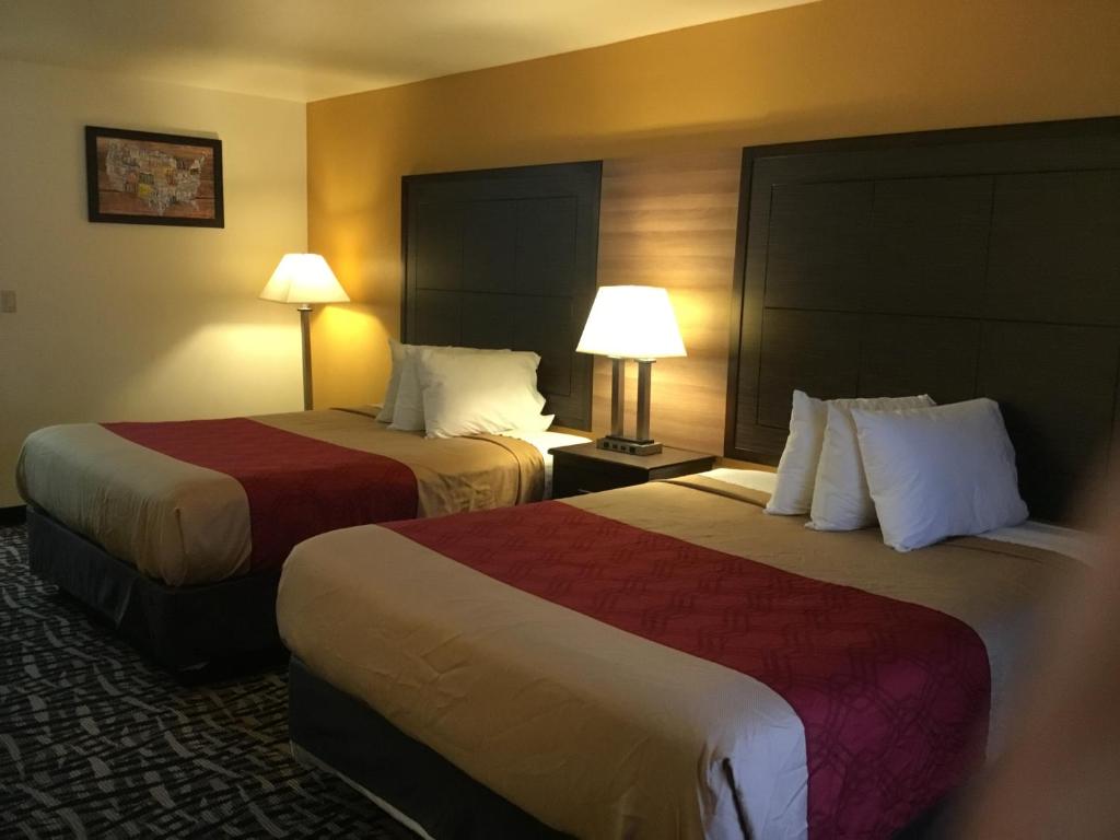 two beds in a hotel room with two lamps at Executive Inn westley,CA in Westley