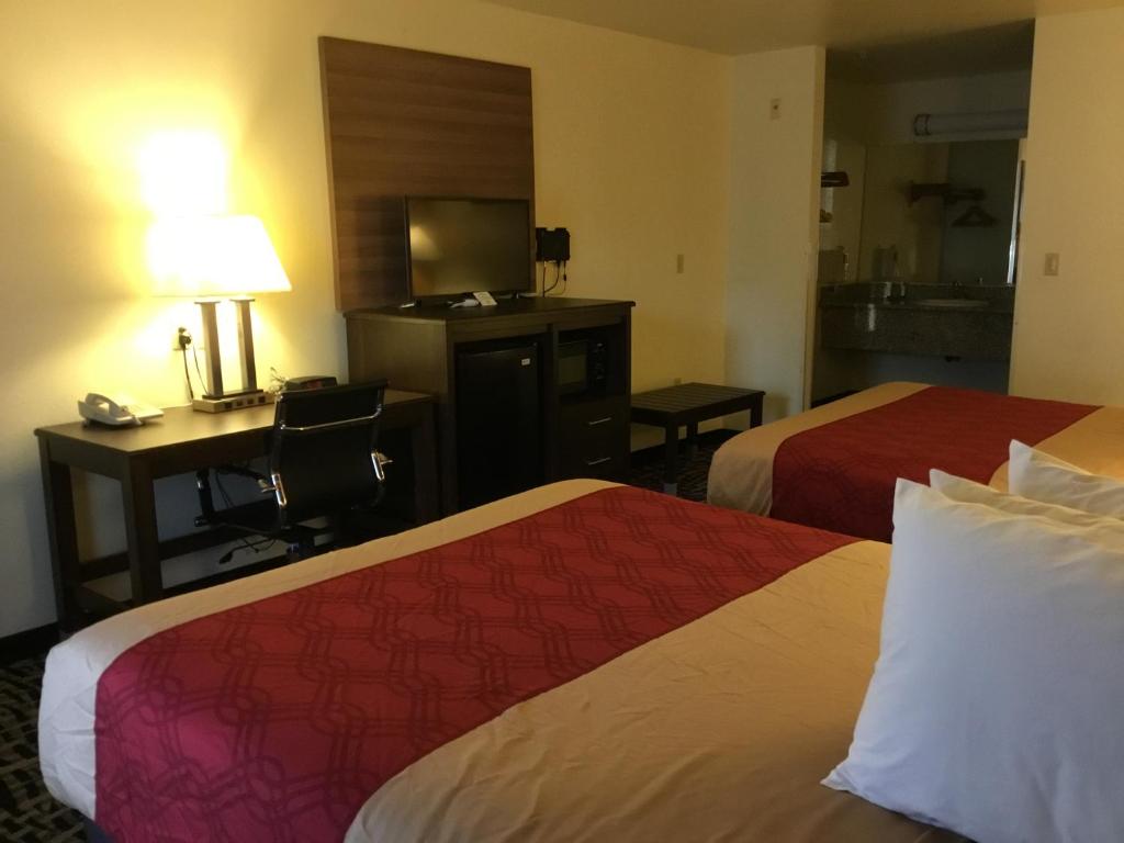 a hotel room with two beds and a desk and a television at Executive Inn westley,CA in Westley