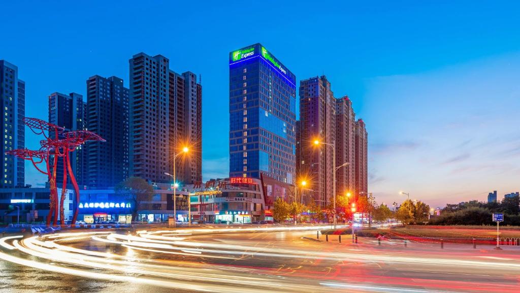 eine Skyline der Stadt mit hohen Gebäuden und Straßenbeleuchtung in der Unterkunft Holiday Inn Express Linyi Riverside, an IHG Hotel in Linyi
