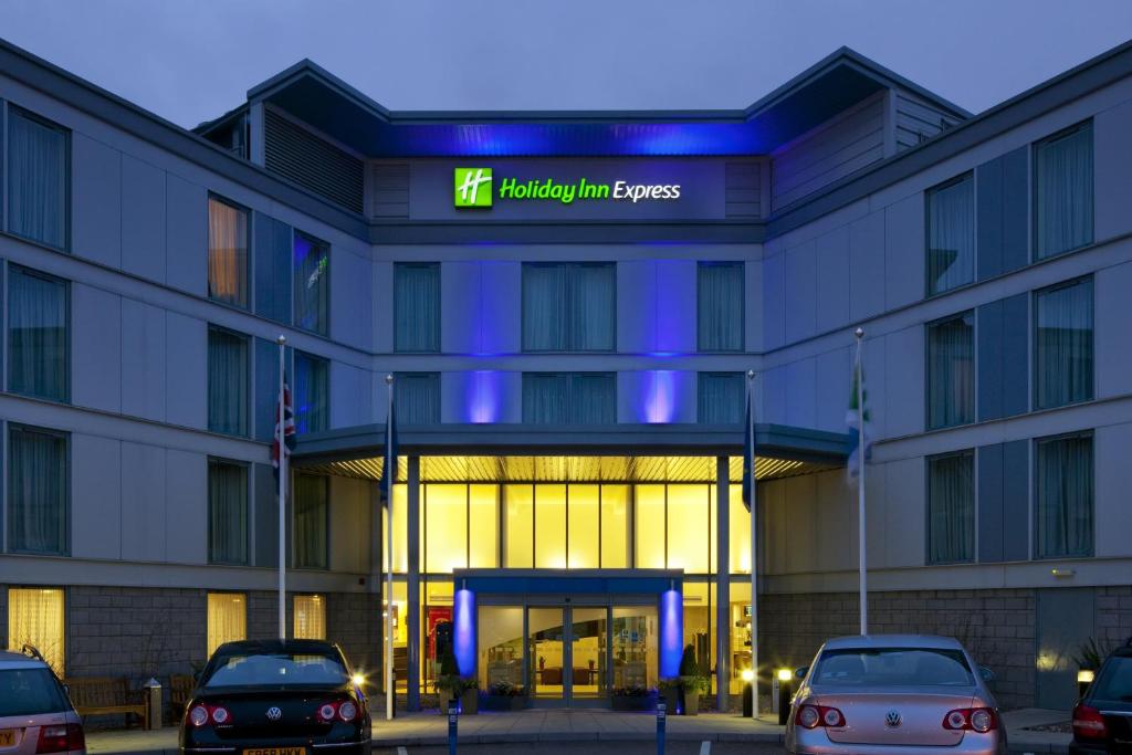 斯坦斯特德芒特費切特的住宿－Holiday Inn Express London Stansted Airport, an IHG Hotel，前面有汽车停放的建筑