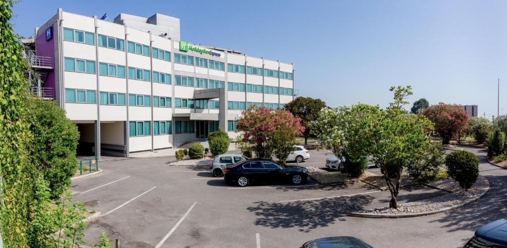 een groot gebouw met auto's geparkeerd op een parkeerplaats bij Holiday Inn Express Lisbon Airport, an IHG Hotel in Lissabon