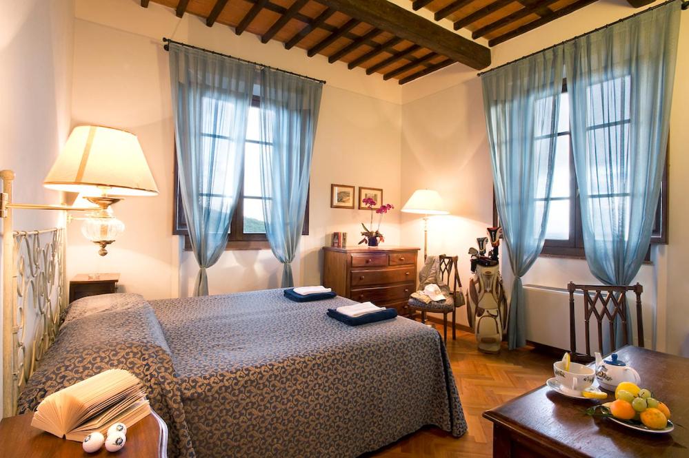 a bedroom with a bed and a table and windows at La Foresteria Montecatini Golf in Lamporecchio