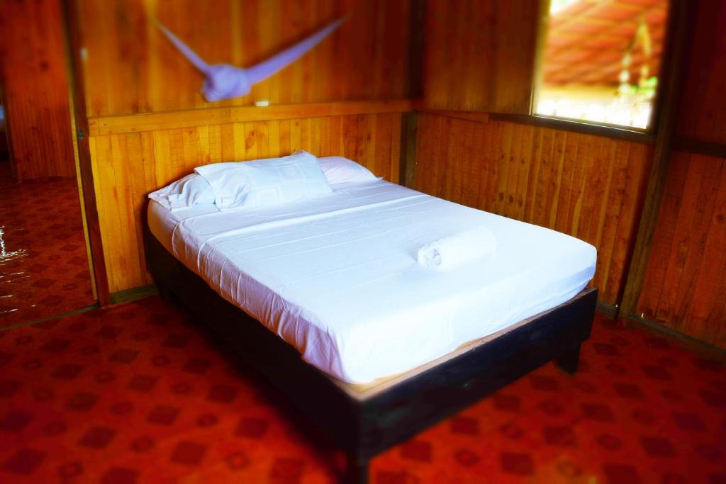 a bed in a room with a bird flying above it at Posada La Sirena Negra in Nuquí