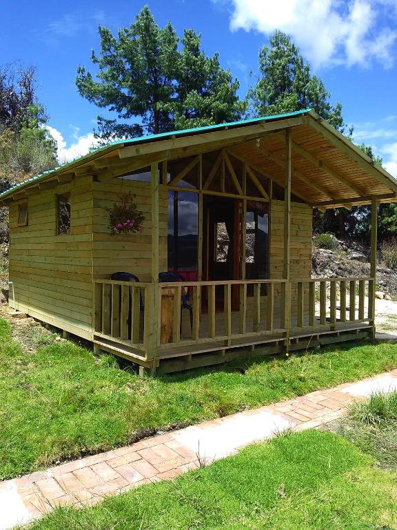 a large wooden cabin with a porch on the grass at Cabaña San Martin in Guatavita