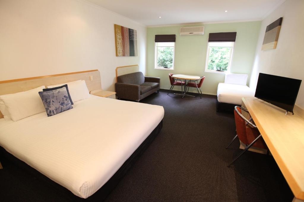 a hotel room with a bed, chair, desk and television at Red Bridge Motor Inn in Woombye