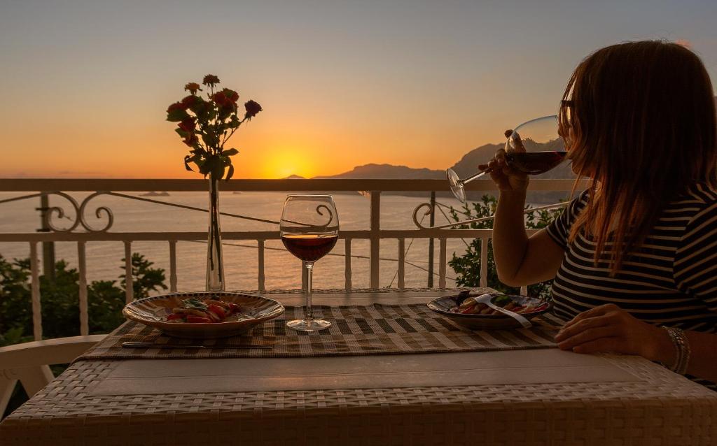 una donna seduta a un tavolo con un bicchiere di vino di Casa Sea la Vie a Praiano
