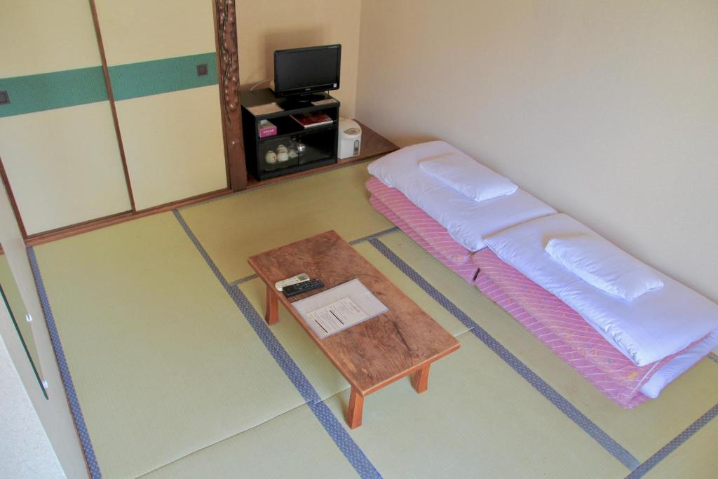 京都市にあるシティーペンション トミーリッチイン京都のベッドとテーブル付きの小さな部屋