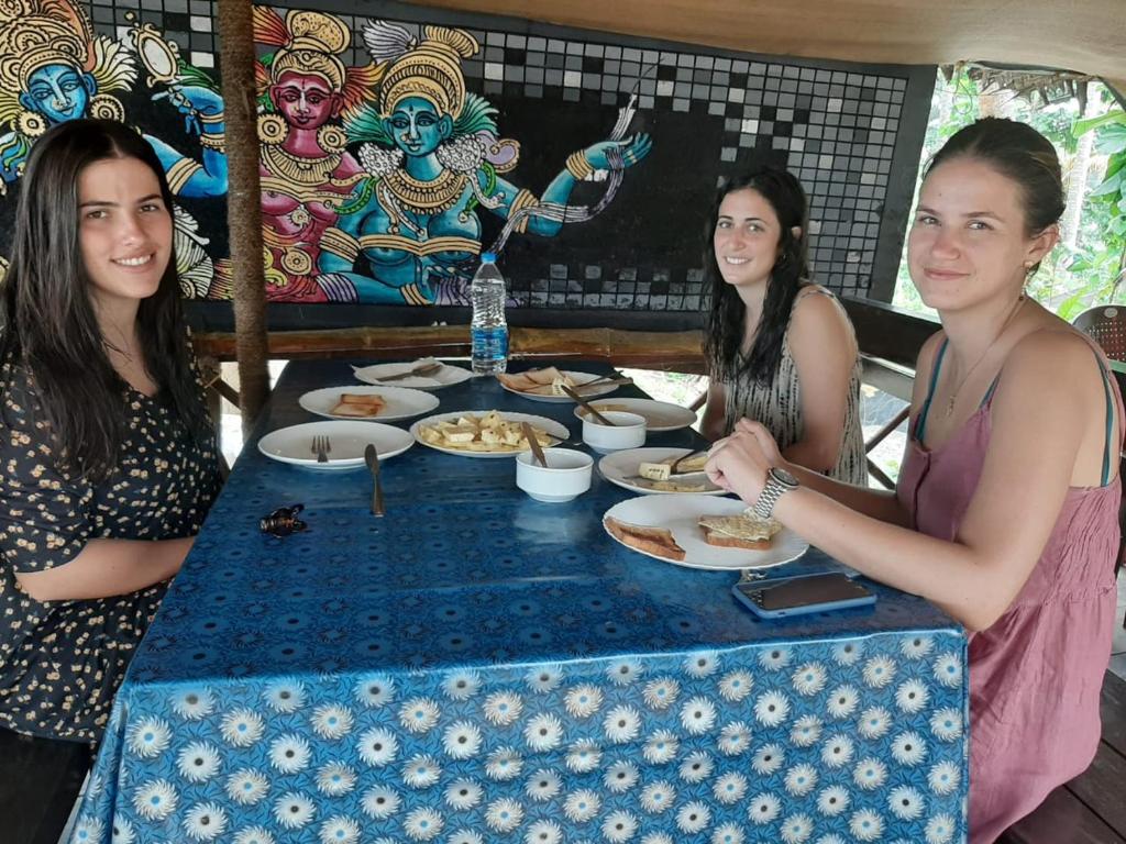 three women sitting at a table with plates of food at Cherai Ocean View Home in Cherai Beach