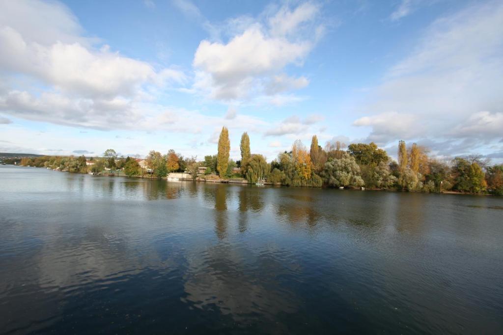 a large lake with trees in the background at Comme un Poisson dans l'Eau in Villennes-sur-Seine