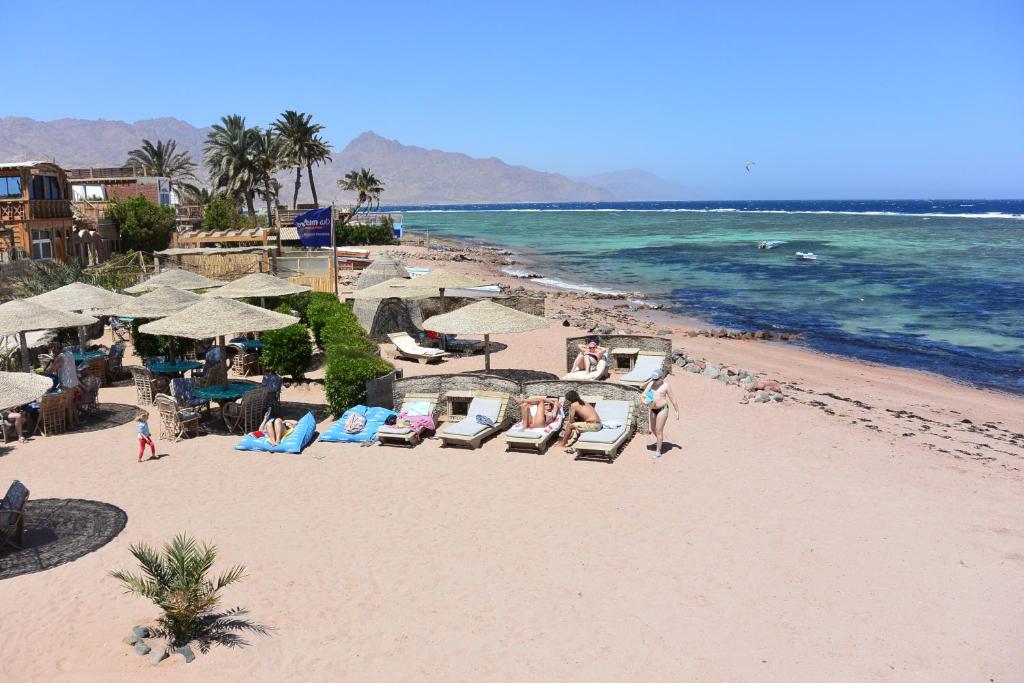 una playa con sillas y sombrillas y el océano en Eldorado Lodge and Restaurant en Dahab