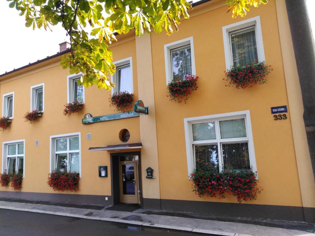 żółty budynek z skrzyniami kwiatowymi na oknach w obiekcie Hotel Vagónka w mieście Studénka