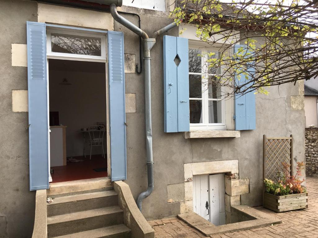 una casa con persianas azules y escaleras delante en La Bernache, en Saint-Satur