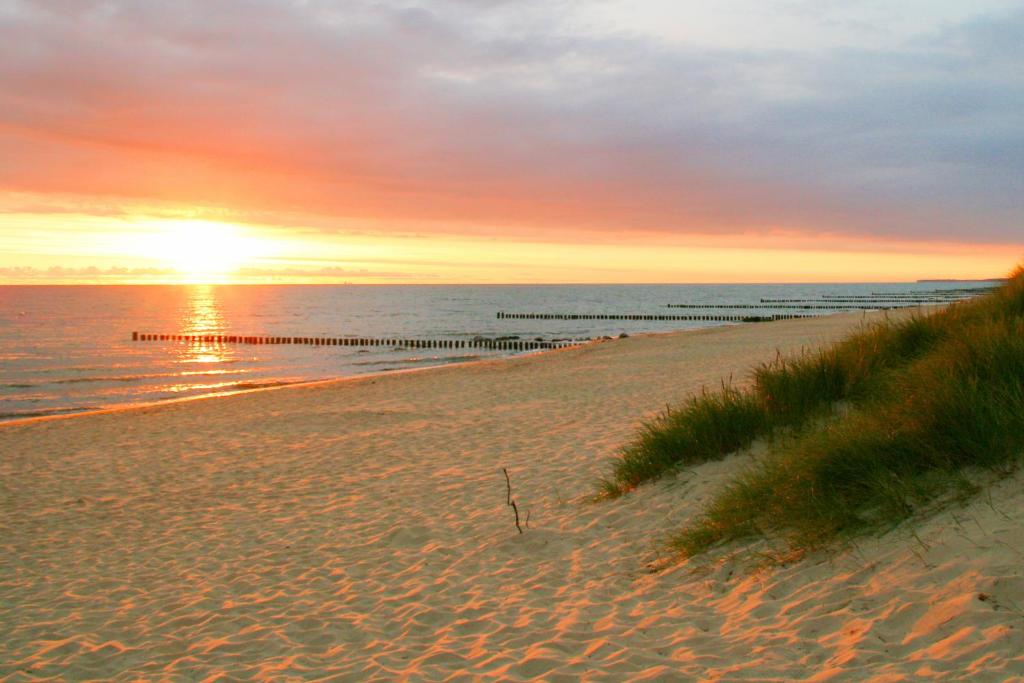 a beach with the sun setting over the water at Ferienhaus in Kuehlungsborn in Kühlungsborn