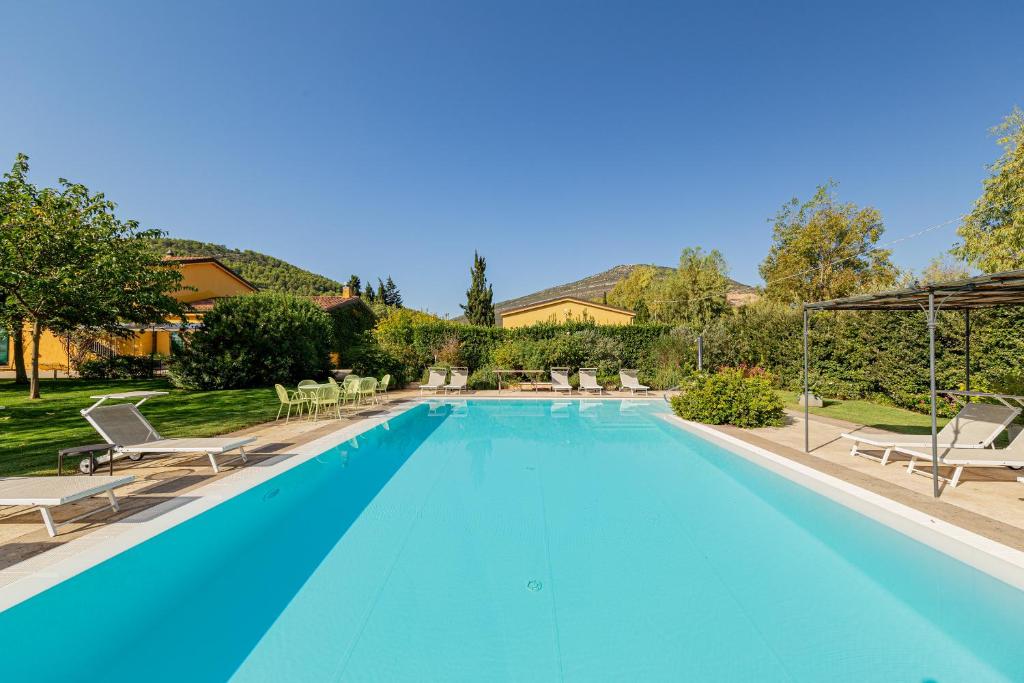 a large blue swimming pool with chairs and trees at Wine Resort Ledà d'Ittiri in Fertilia