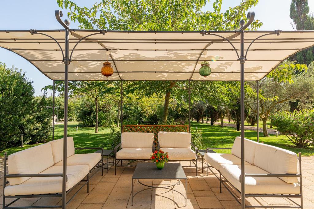 a pergola with white chairs and a table at Wine Resort Ledà d'Ittiri in Fertilia