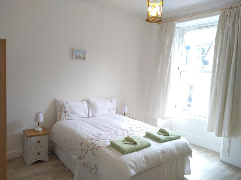 a bedroom with a white bed with two green towels on it at Stylish two bedroom apartment in St Andrews centre in St. Andrews