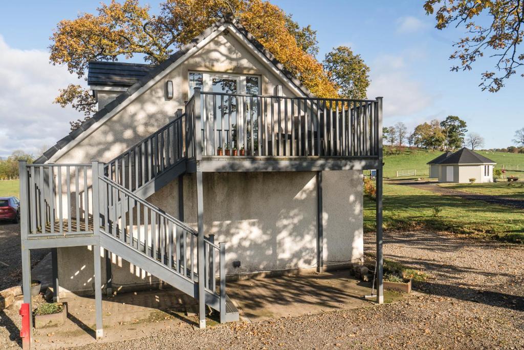 a small house with a staircase leading to a garage at Dunroamin Apartment in Drymen