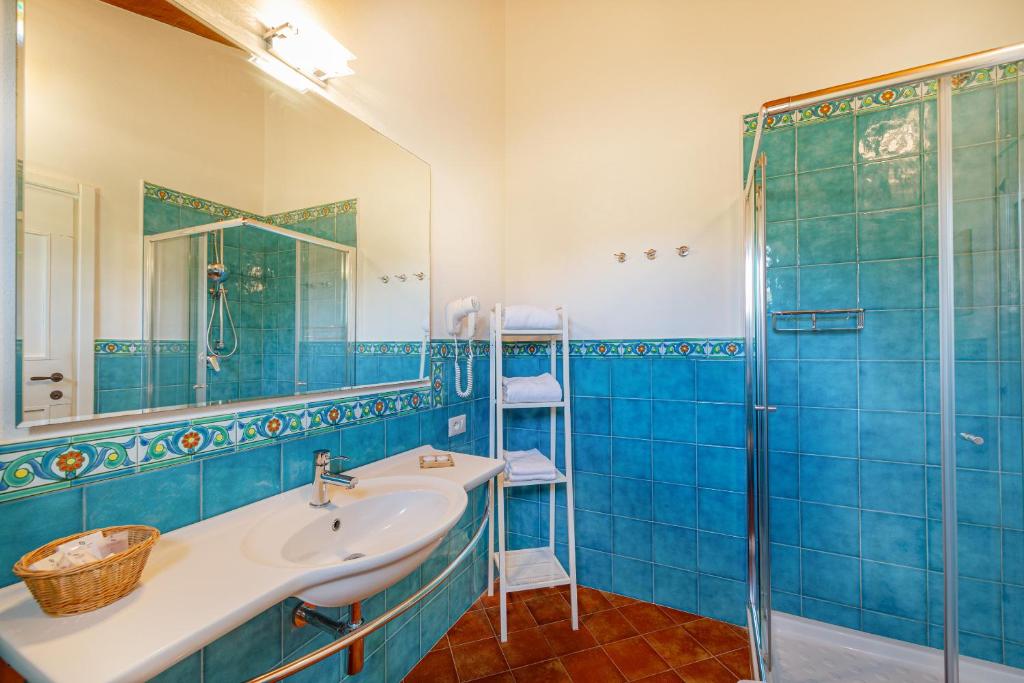 a blue bathroom with a sink and a shower at Wine Resort Ledà d'Ittiri in Fertilia