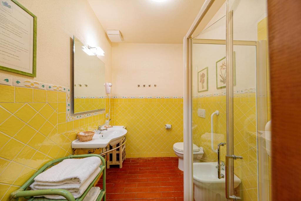 a yellow bathroom with a sink and a toilet at Wine Resort Ledà d'Ittiri in Fertilia