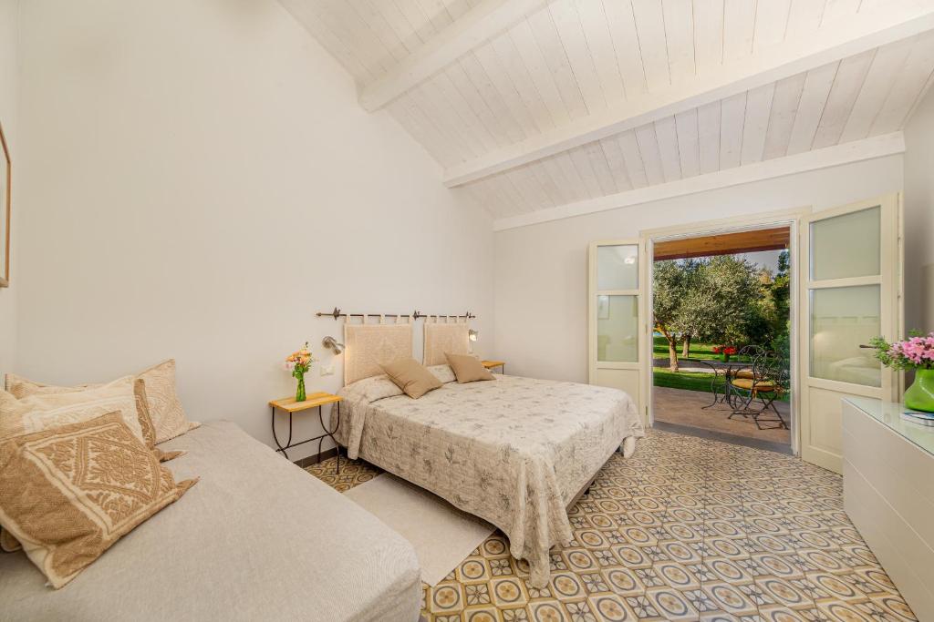 a white bedroom with a bed and a couch at Wine Resort Ledà d'Ittiri in Fertilia